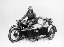 Man riding an AJS motorbike with a woman in the sidecar, 1939