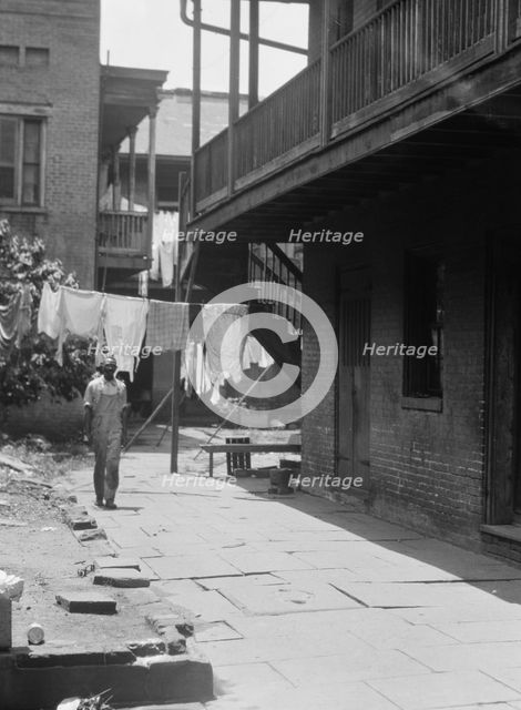 Man standing in a courtyard, New Orleans, between 1920 and 1926. Creator: Arnold Genthe.
