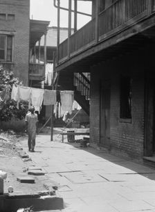 Man standing in a courtyard, New Orleans, between 1920 and 1926. Creator: Arnold Genthe