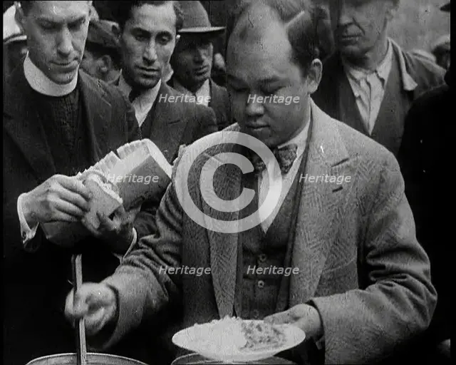 Man Serving Meals For Group of People from the Street Kitchen, 1932. Creator: British Pathe Ltd.