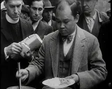 Man Serving Meals For Group of People from the Street Kitchen, 1932. Creator: British Pathe Ltd