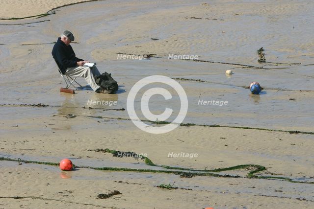 Man sitting on the sand in St Ives harbour at low tide, Cornwall. Creator: Peter Thompson.