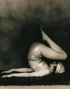 Marguerite Agniel posing with her back arched and feet in the air, wearing a two-piece cos..., 1929. Creator: Unknown