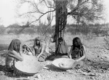 Maricopa group, Arizona. Four women and a child seated on ground with three large basket trays,c1907 Creator: Edward Sheriff Curtis