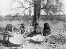 Maricopa group, Arizona. Four women and a child seated on ground with three large basket trays,c1907 Creator: Edward Sheriff Curtis