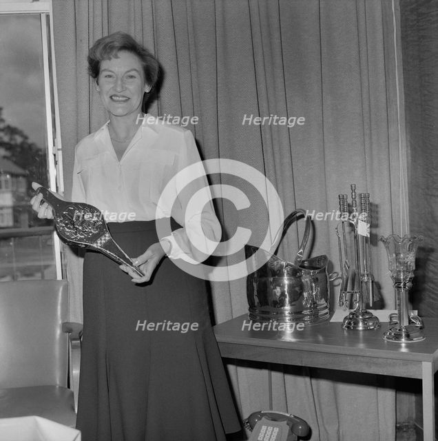 Mary Coldicott holding a brass ornamental gift, during her retirement presentation

, 01/08/1986. Creator: John Laing plc.