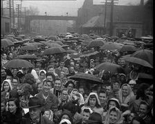 Masses of People Cheering the Train As It Passes By Many Have Umbrellas As It Is Raining, 1932. Creator: British Pathe Ltd