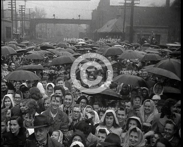 Masses of People Cheering the Train As It Passes By Many Have Umbrellas As It Is Raining, 1932. Creator: British Pathe Ltd.