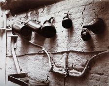 Measuring jugs and a funnel hung on a wall in the Red Cross pharmacy in London, c1890s. Creator: Unknown