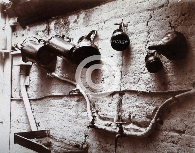 Measuring jugs and a funnel hung on a wall in the Red Cross pharmacy in London, c1890s. Creator: Unknown.