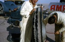 Mechanics inflating Bluebird CN7 tyre for World Land Speed Record attempt, Lake Eyre, 1964. Creator: Unknown