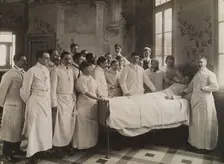 Medical staff standing round a woman patient in bed in a hospital ward, c1910. Creator: Freres Seeberger