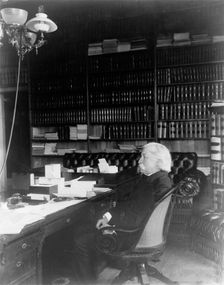 Melville Weston Fuller, full-length portrait, seated at desk, facing left, c1899. Creator: Frances Benjamin Johnston