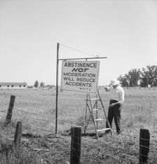 Member of the committee...erects sign on U.S. 99 highway, near Hanford, California, 1939. Creator: Dorothea Lange