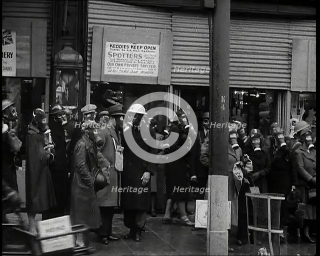 Men and Women Waiting on a Pavement Wearing Gas Masks, 1939. Creator: British Pathe Ltd.