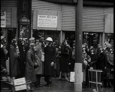 Men and Women Waiting on a Pavement Wearing Gas Masks, 1939. Creator: British Pathe Ltd