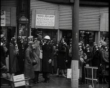 Men and Women Waiting on a Pavement Wearing Gas Masks, 1939. Creator: British Pathe Ltd