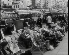Men and Women Sitting in Deckchairs on the Promenade at Brighton With a Row of Buses..., 1939. Creator: British Pathe Ltd
