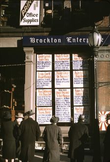 Men and a woman reading headlines posted in street-corner window of Brockton..., Mass., 1940. Creator: Jack Delano