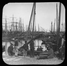 Men and boys with sailing boats in port, unknown location, c1900s. Creator: Robert Augustus Henry L'Estrange