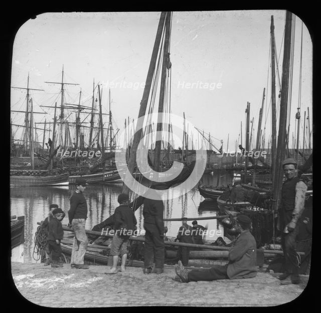Men and boys with sailing boats in port, unknown location, c1900s. Creator: Robert Augustus Henry L'Estrange.