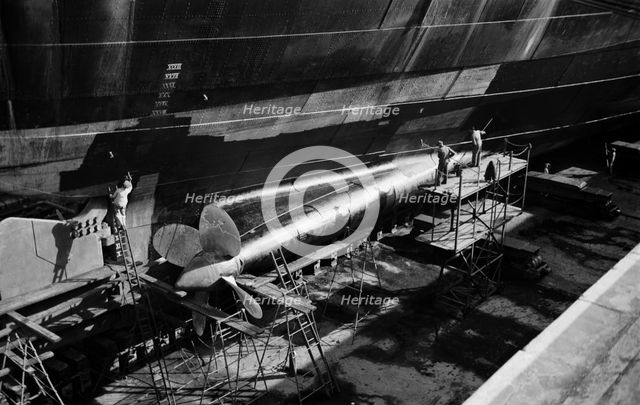Men clean and paint the hull of a ship in the New Dry Dock, Tilbury Docks, Tilbury, c1945-c1965. Artist: SW Rawlings