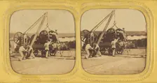 Men loading large iron wheels on platform, about 1865. Creator: Unknown