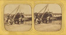 Men loading large iron wheels on platform, about 1865. Creator: Unknown