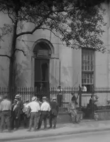 Men standing or sitting in front of the former Bank of Louisiana, 334 Royal Street..., c1920-1926. Creator: Arnold Genthe