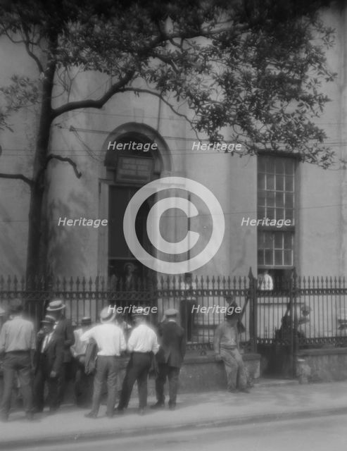 Men standing or sitting in front of the former Bank of Louisiana, 334 Royal Street..., c1920-1926. Creator: Arnold Genthe.