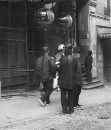 Men standing or walking down a sidewalk, Chinatown, San Francisco, between 1896 and 1906. Creator: Arnold Genthe