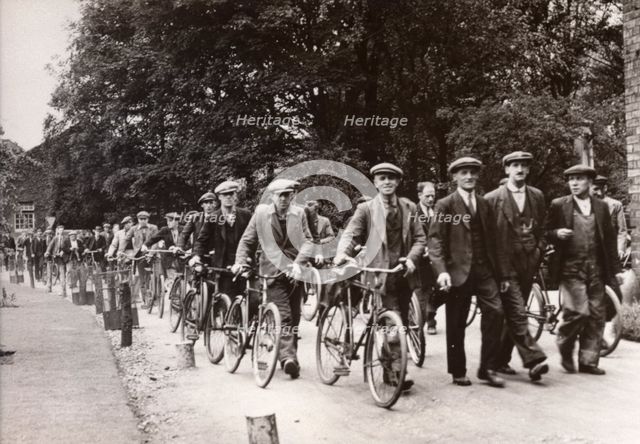 Men walk and wheel bicycles away from the Rowntree factory, York, Yorkshire, 1940. Artist: Unknown