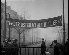 Men Walking Below Banner Reading: 1 Der Osten Wahlt Hitler 1 , 1933. Creator: British Pathe Ltd