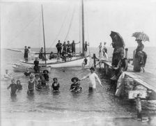 Men, women, and children in bathing suits on dock, sailboats, and in water..., c1880. Creator: Unknown