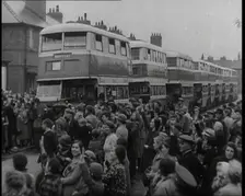 Men, Women, and Children Standing by a Line of Buses Parked in a Residential Street, 1939. Creator: British Pathe Ltd