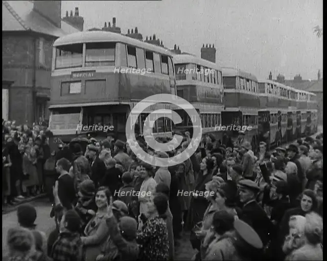 Men, Women, and Children Standing by a Line of Buses Parked in a Residential Street, 1939. Creator: British Pathe Ltd.