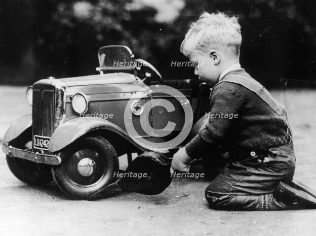 Michael Ware repairing a pedal car. Artist: Unknown