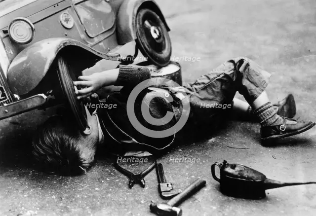 Michael Ware repairing his pedal car. Artist: Unknown