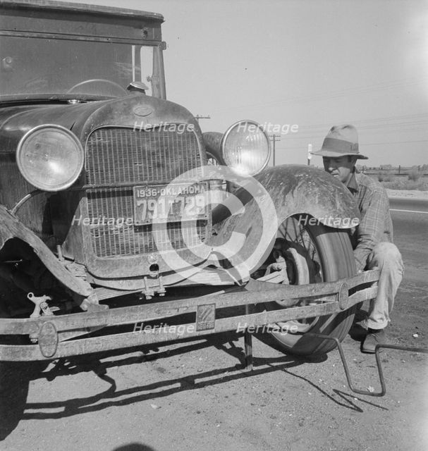 Migrant worker from Oklahoma repairing tire on California highway, 1936. Creator: Dorothea Lange.