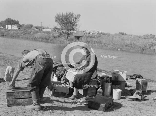 Migrant family cleaning up, near Vale, Malheur County, Oregon, 1939. Creator: Dorothea Lange.