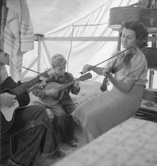 Migrant family from Arkansas playing hill-billy songs, FSA...migratory camp, Calipatria, CA, 1939. Creator: Dorothea Lange
