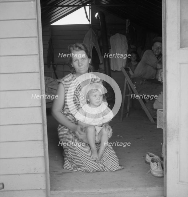 Migrant mother and child at doorway of steel shelter, FSA camp, Tulare County, 1939. Creator: Dorothea Lange.