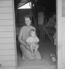 Migrant mother and child at doorway of steel shelter, FSA camp, Tulare County, 1939. Creator: Dorothea Lange