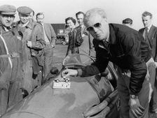 Mike Hawthorn admiring a toy model Ferrari on his racing Ferrari. Creator: Unknown