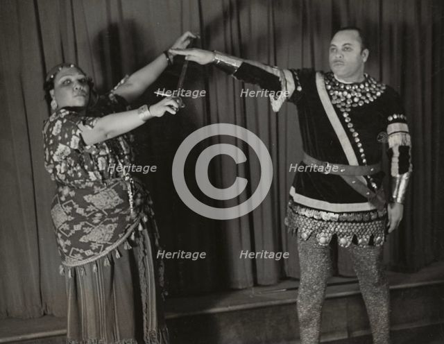 Minto Cato as Azucena and Parker Watkins as Manrico, swearing vengeance on a sword, 1936. Creator: Eagle Ezzes & Mipaas.