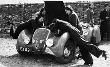 Miss MD Patten looking at the engine of a 1938 Peugeot 402 Special Sport, RAC Rally, 1939