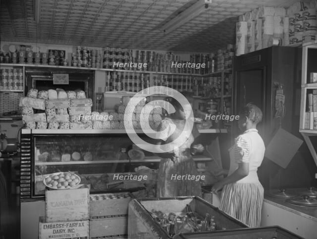 Mr. J. Benjamin's daughter waiting on a customer in her father's store, Washington, D.C., 1942. Creator: Gordon Parks.