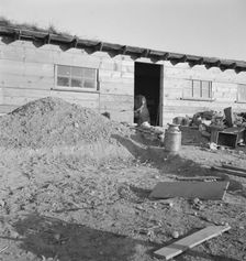 Mrs. Dougherty in doorway of basement house, Warm Springs, Malheur County, Oregon, 1939. Creator: Dorothea Lange