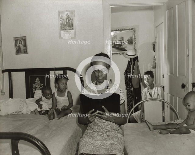 Mrs. Ella Watson, a government charwoman, reading the Bible to her household, Washington, DC, 1942. Creator: Gordon Parks.