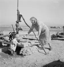 Mrs. Soper with youngest child at the well, Willow creek area, Malheur County, Oregon, 1939. Creator: Dorothea Lange